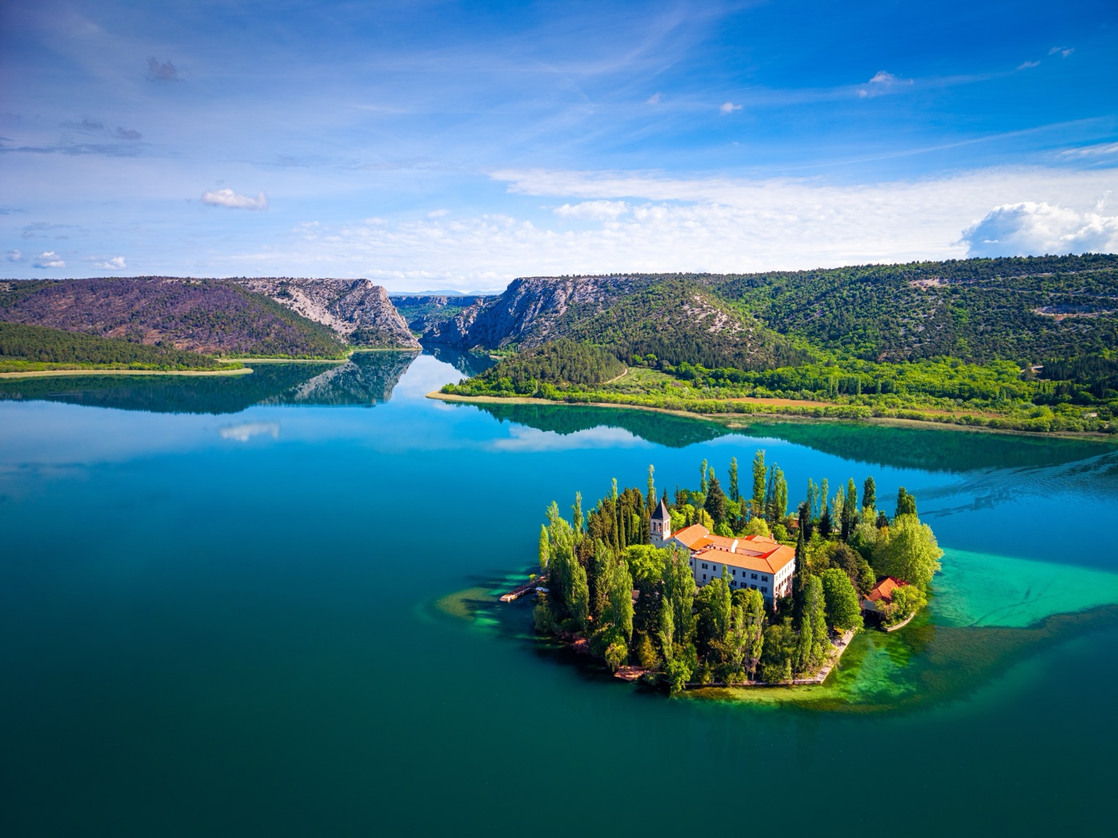 Visovac Island and its monastery in the middle of the lake, with the Krka canyon beyond